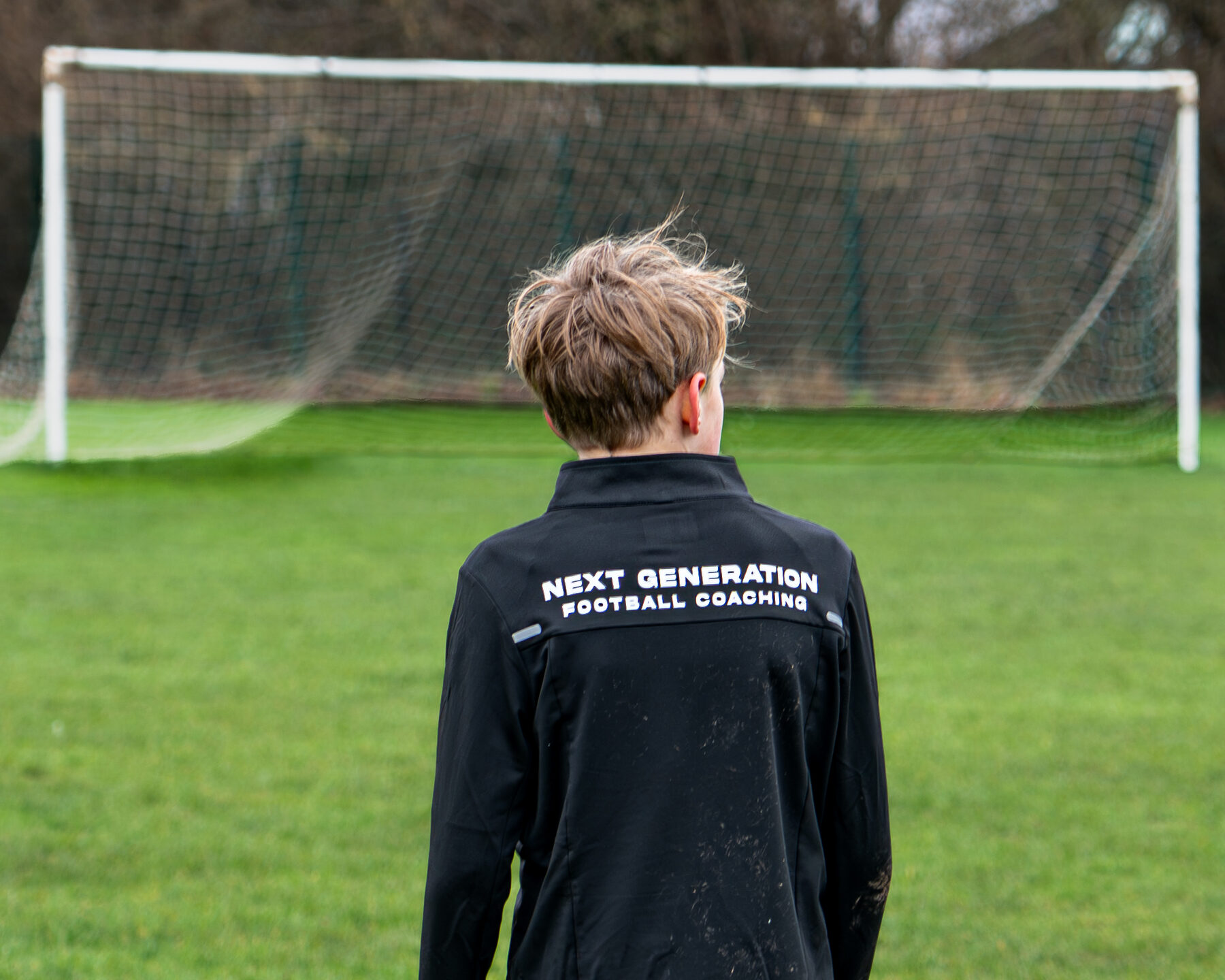 Young NGFC player in branded training jacket in front of the goal
