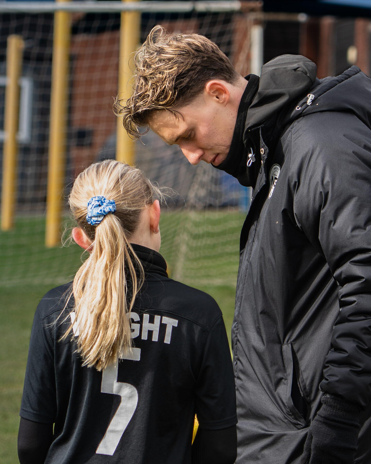 Coach giving one-to-one feedback during a girls session