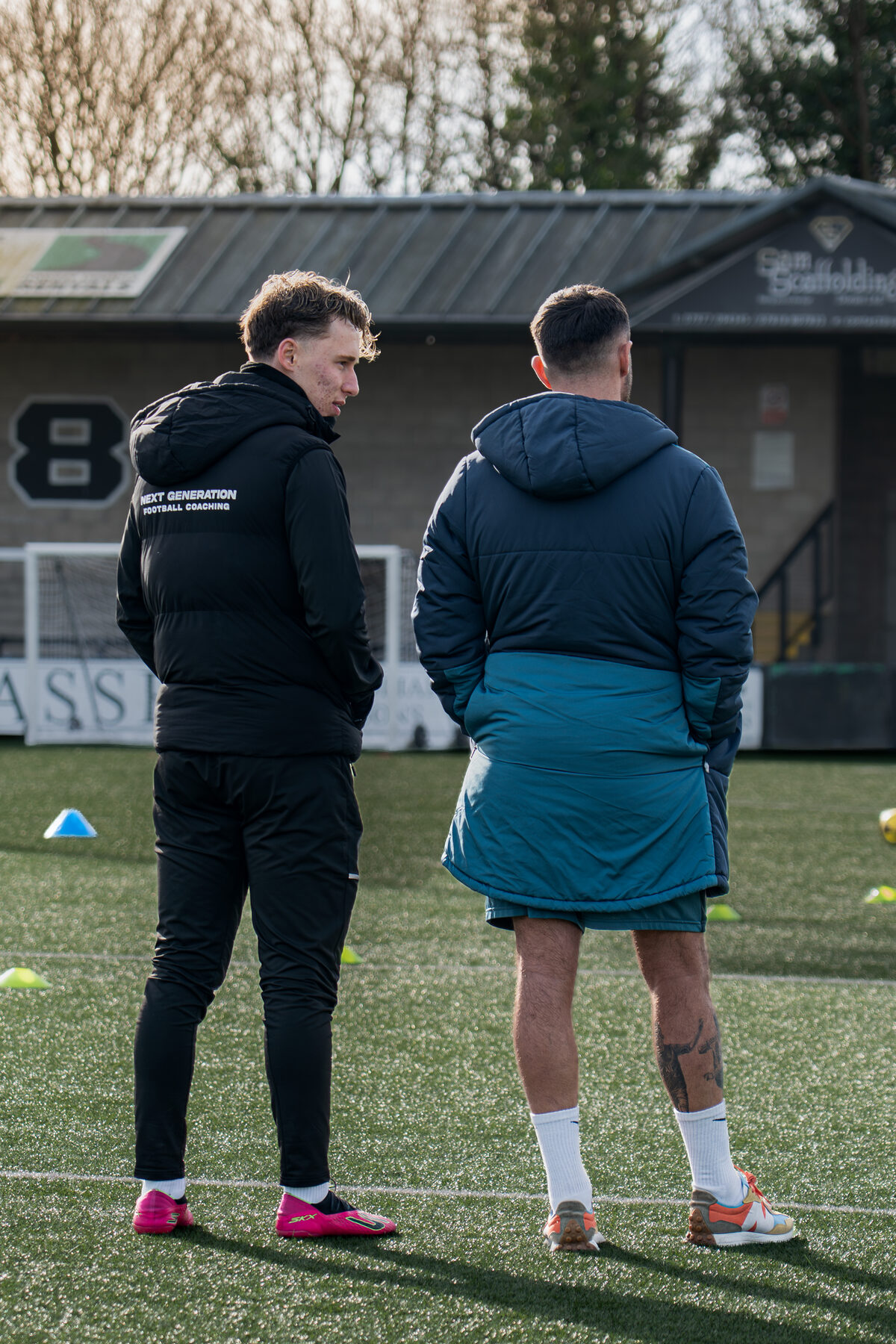 Coaches setting up drills on the stadium pitch
