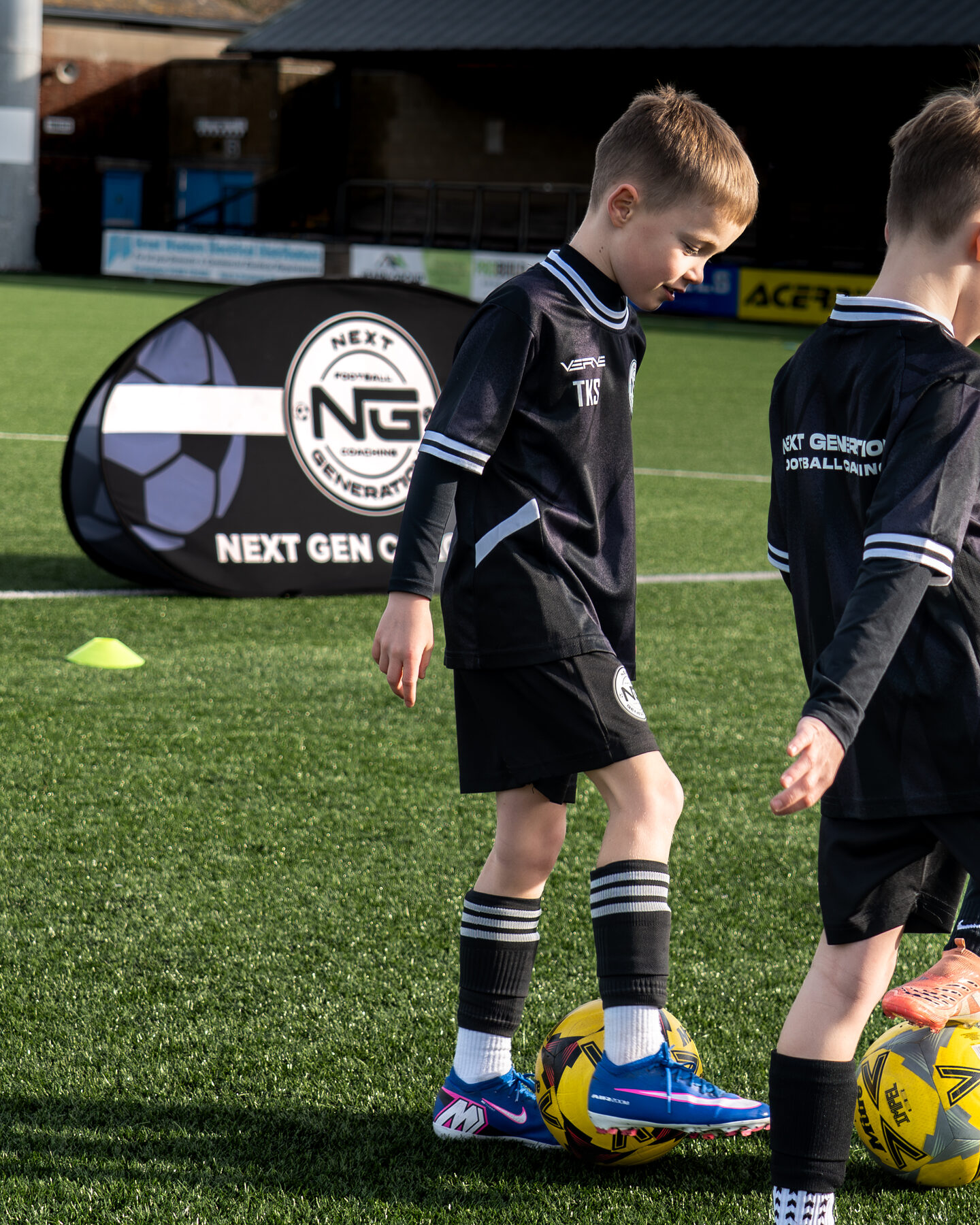 Young players dribbling around cones with the NGFC banner behind