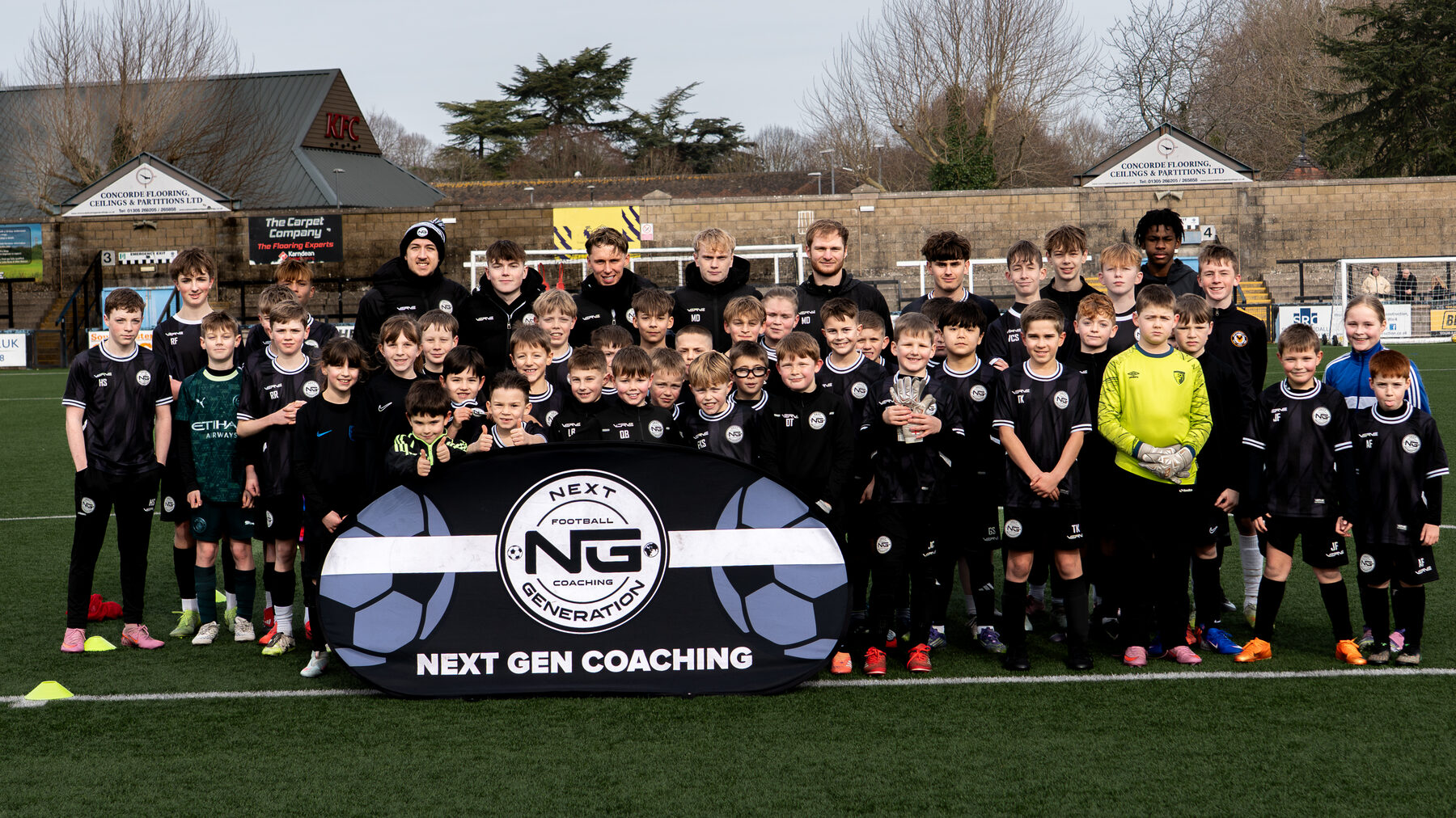 NGFC group photo with players and coaches behind the club banner