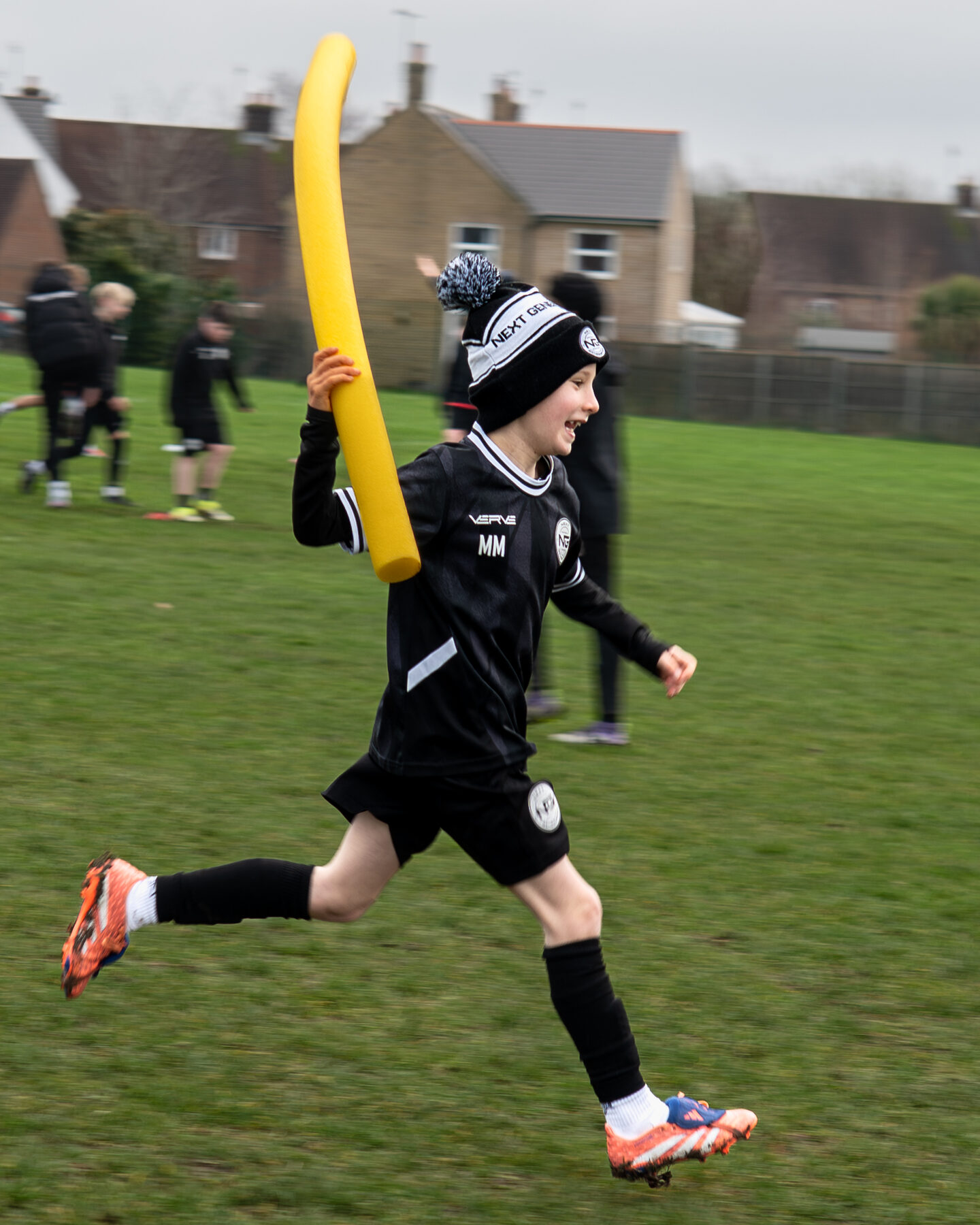 Young player striding past a training pole during a session