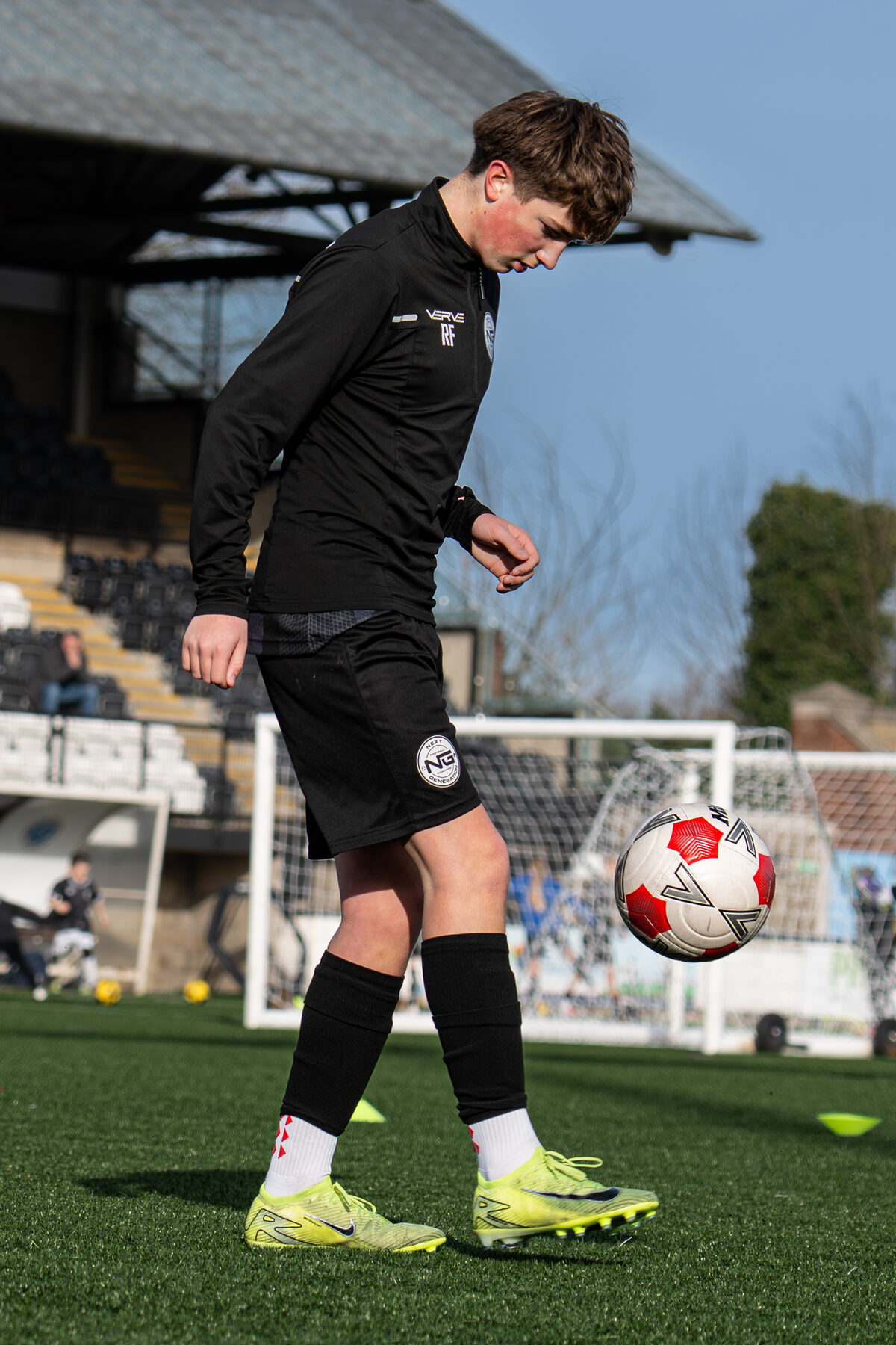 Teenage player striking the ball during a stadium session