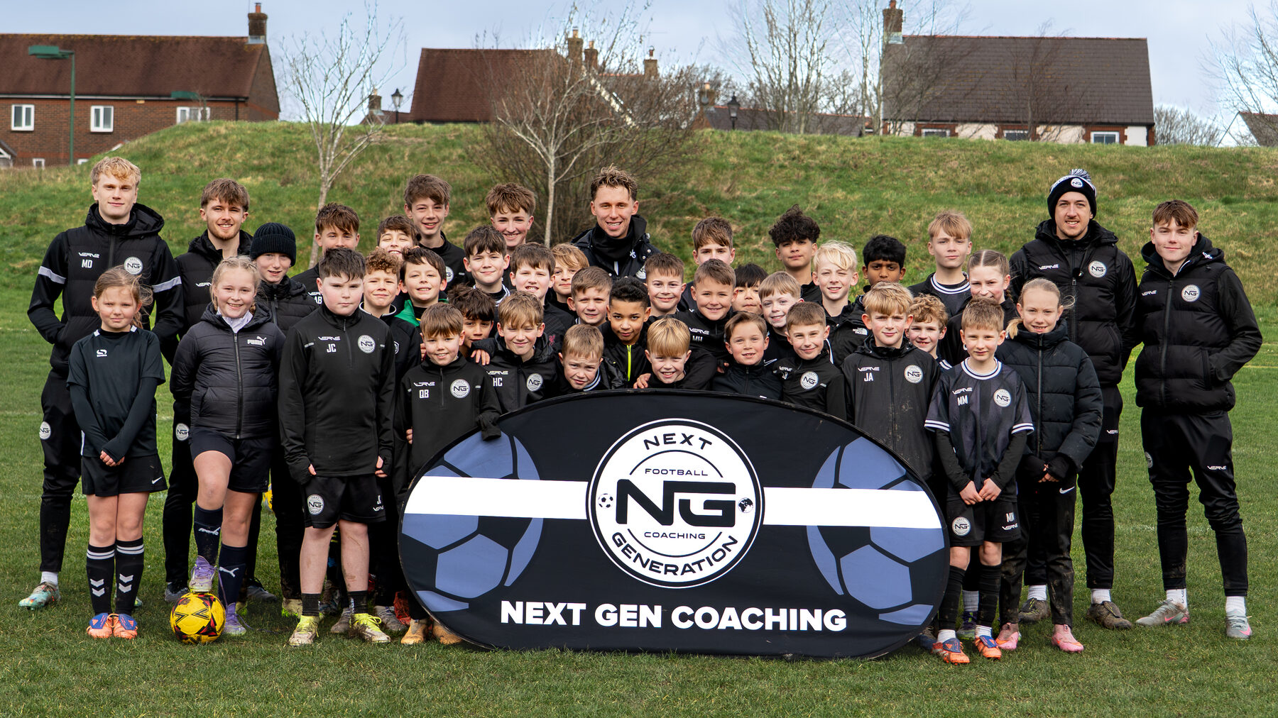 Large NGFC squad group photo behind the Next Gen Coaching banner